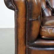 A well-maintained cowhide leather English Chesterfield armchair