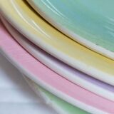 Seven pastel-colored plates mixed with vintage earthenware