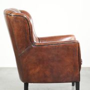 Comfortable sheepskin armchair in unique design finished with black piping