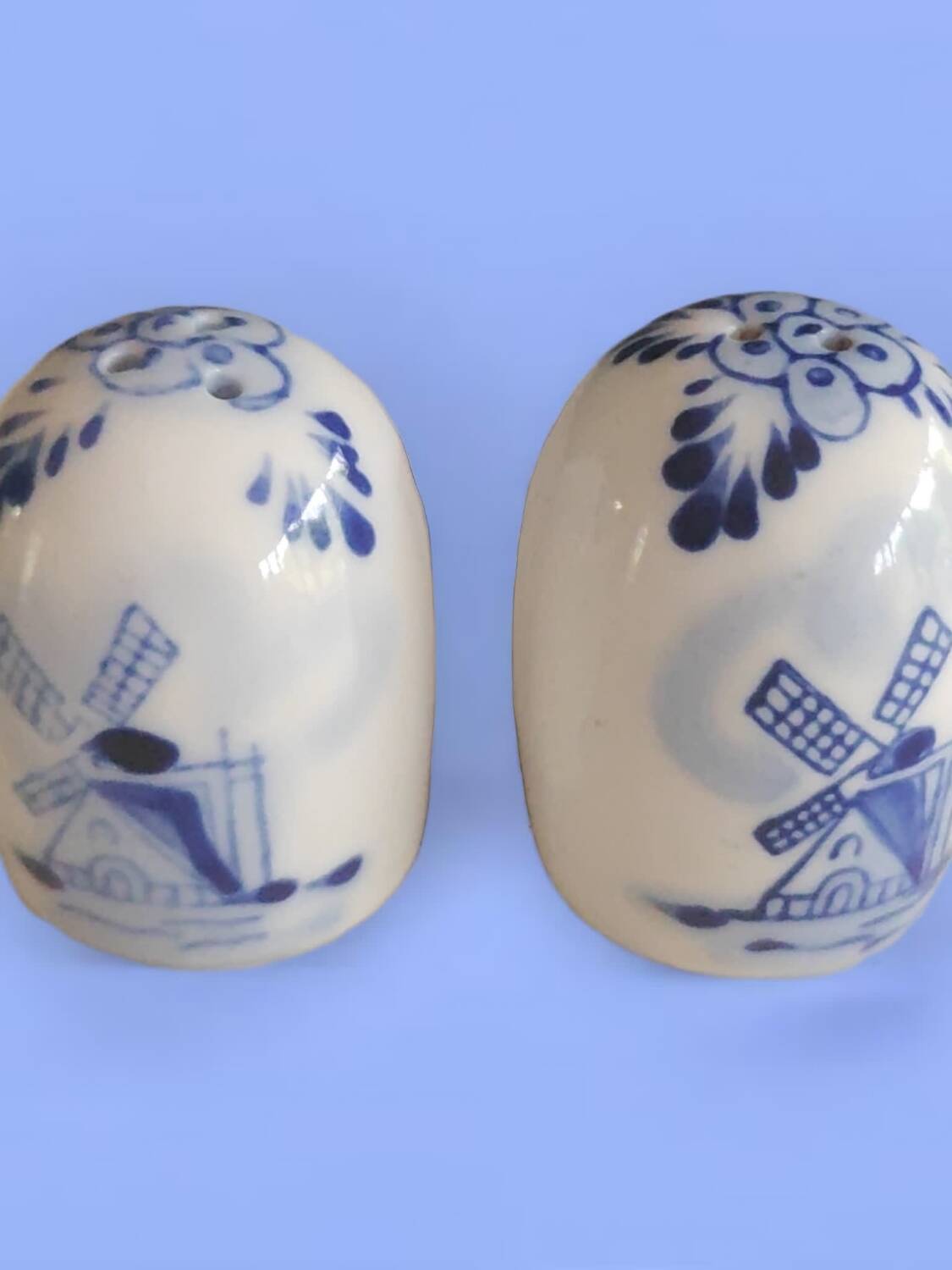 Mini salt and pepper shakers in ceramic with illustrations of Dutch windmills and blue flowers.