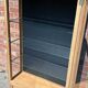 Restored antique oak display cabinet, black background, glass shelves.