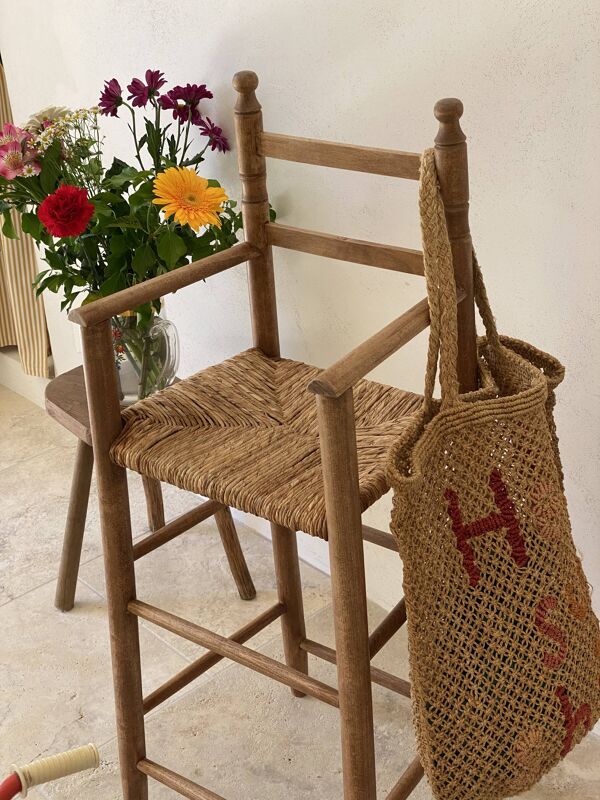 Ancienne chaise haute d’enfant en bois massif avec assise paillée.
