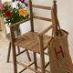 Old wooden high chair for children with a straw seat.