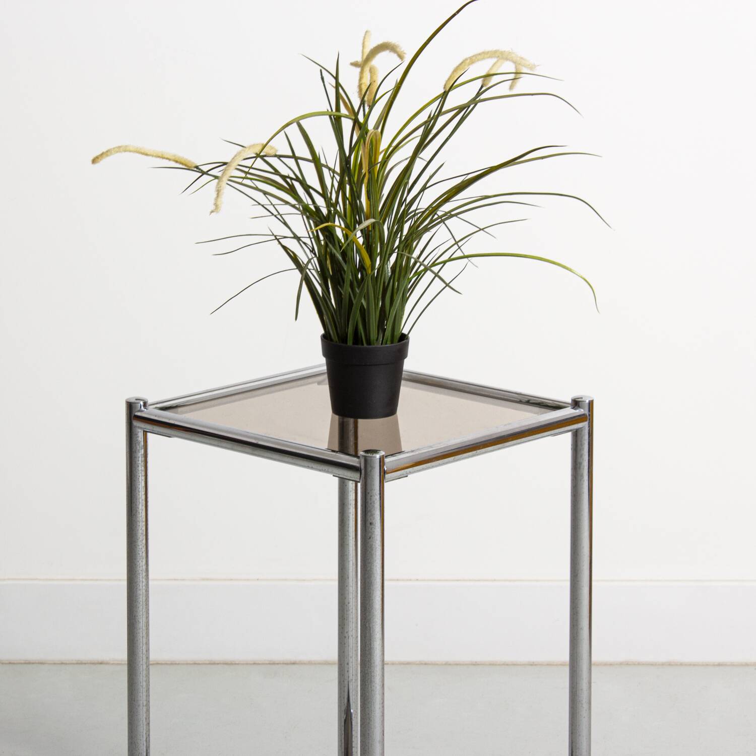 Bolster or end table in chrome steel with smoked window.