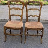 2 solid oak carved and rush-seated chairs in the Louis XV style from the 19th century.