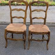 2 solid oak carved and rush-seated chairs in the Louis XV style from the 19th century.