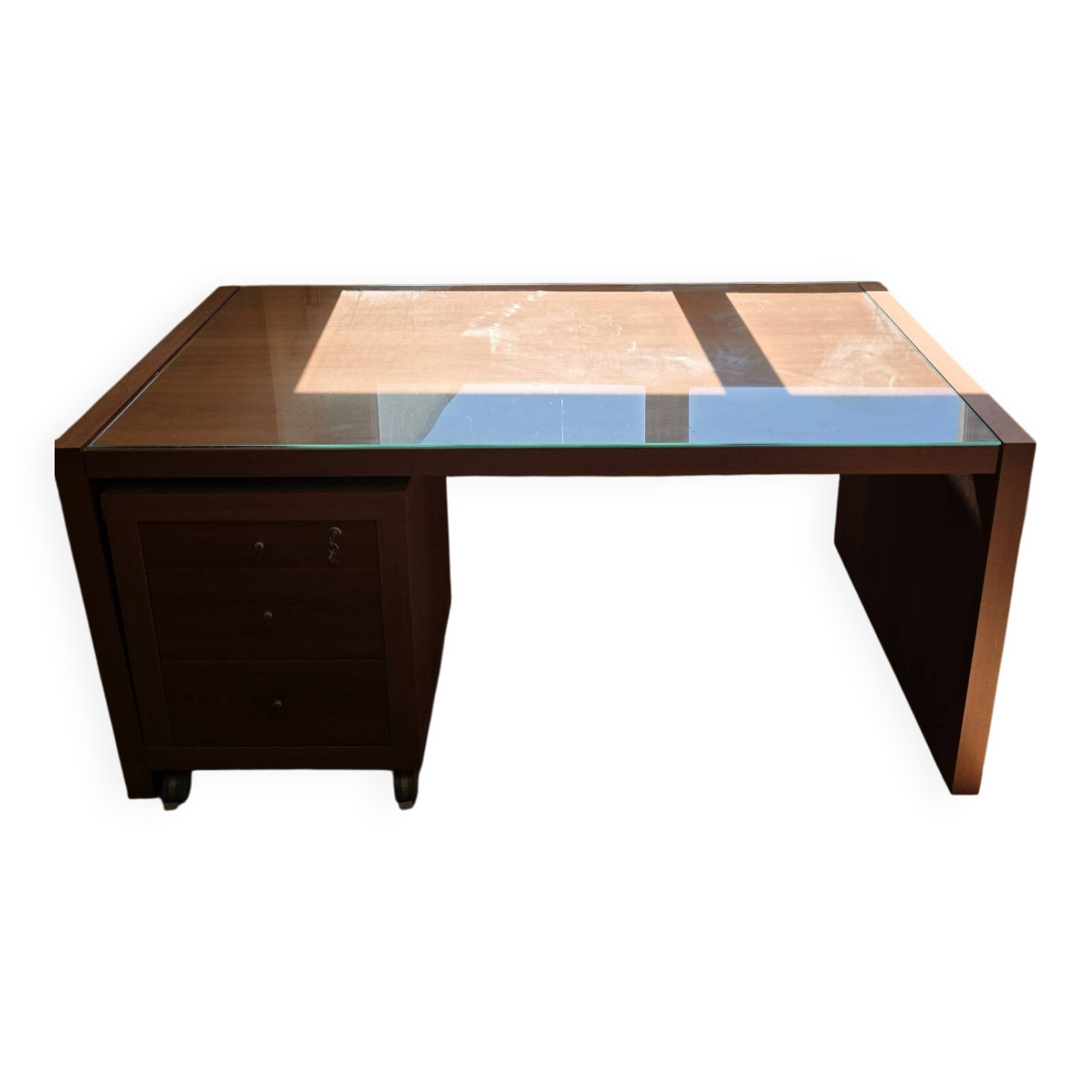 Large wooden desk with a glass top and a wheeled drawer unit.