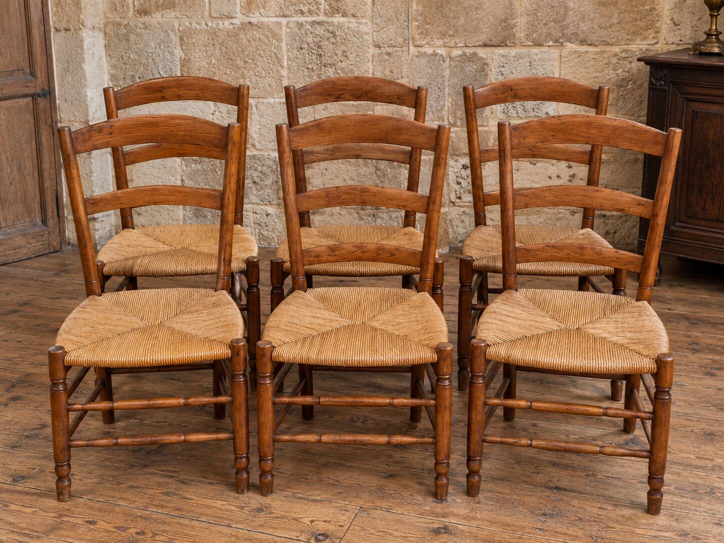 Set of six rustic chairs in natural wood with straw seats.