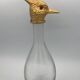 Glass bottle type carafe with gold metal bird head stopper