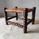 Antique wooden turned spool footrest with straw.
