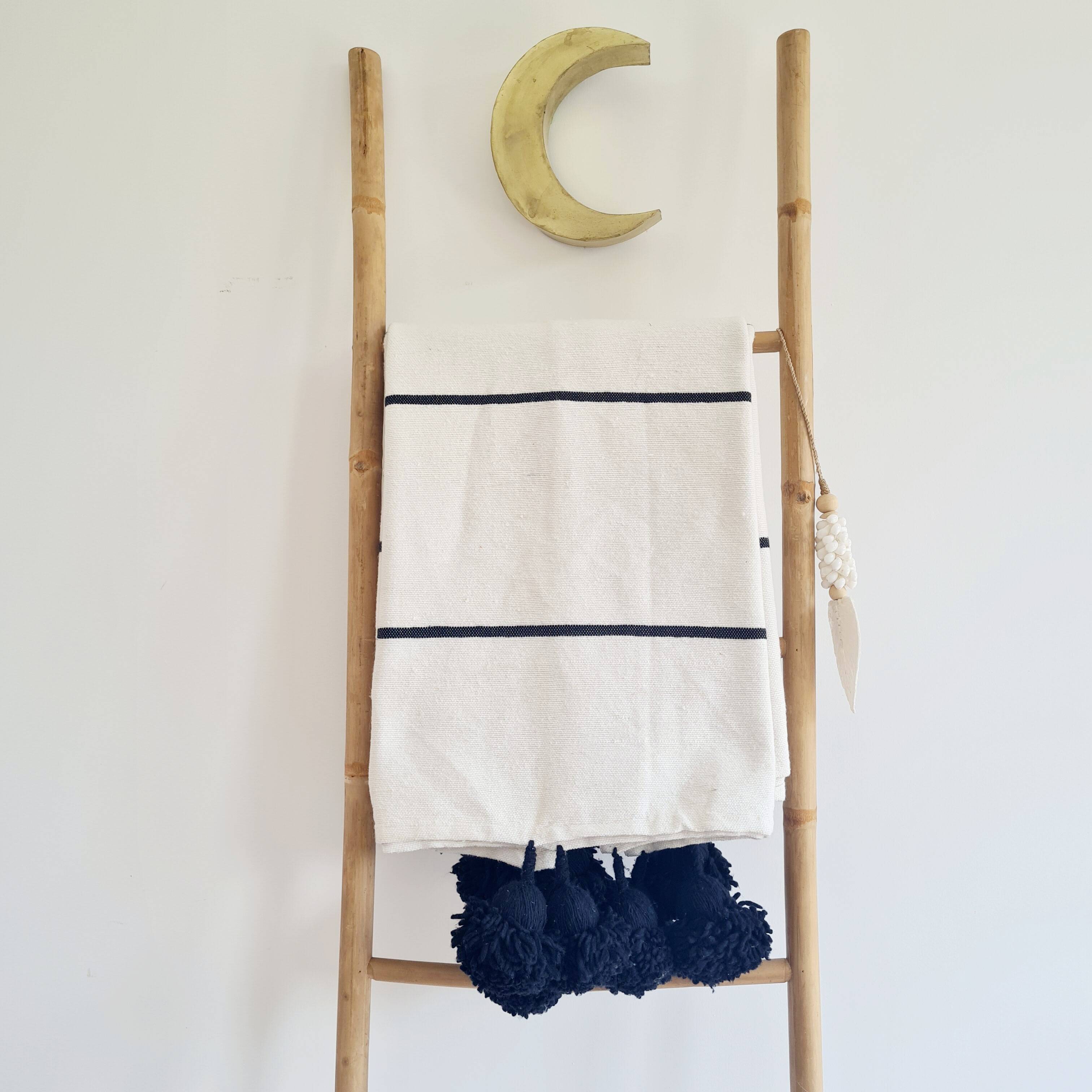 Handwoven throw with black stripes and pom-poms