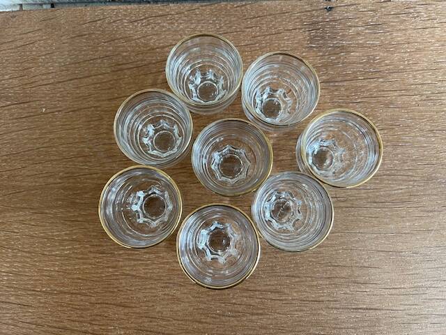 Suite of eight liqueur glasses in white glass and gold highlights. Circa 1970