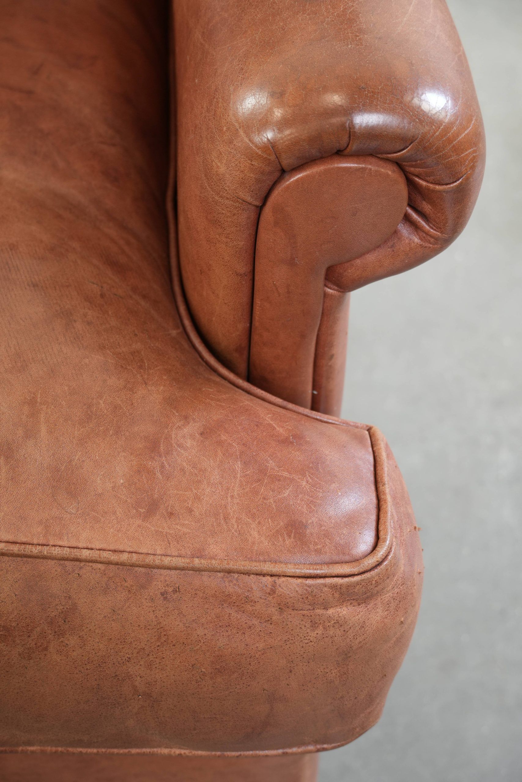 Fauteuil anglais à oreilles de couleur cognac clair en cuir de vache.