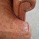 Fauteuil anglais à oreilles de couleur cognac clair en cuir de vache.