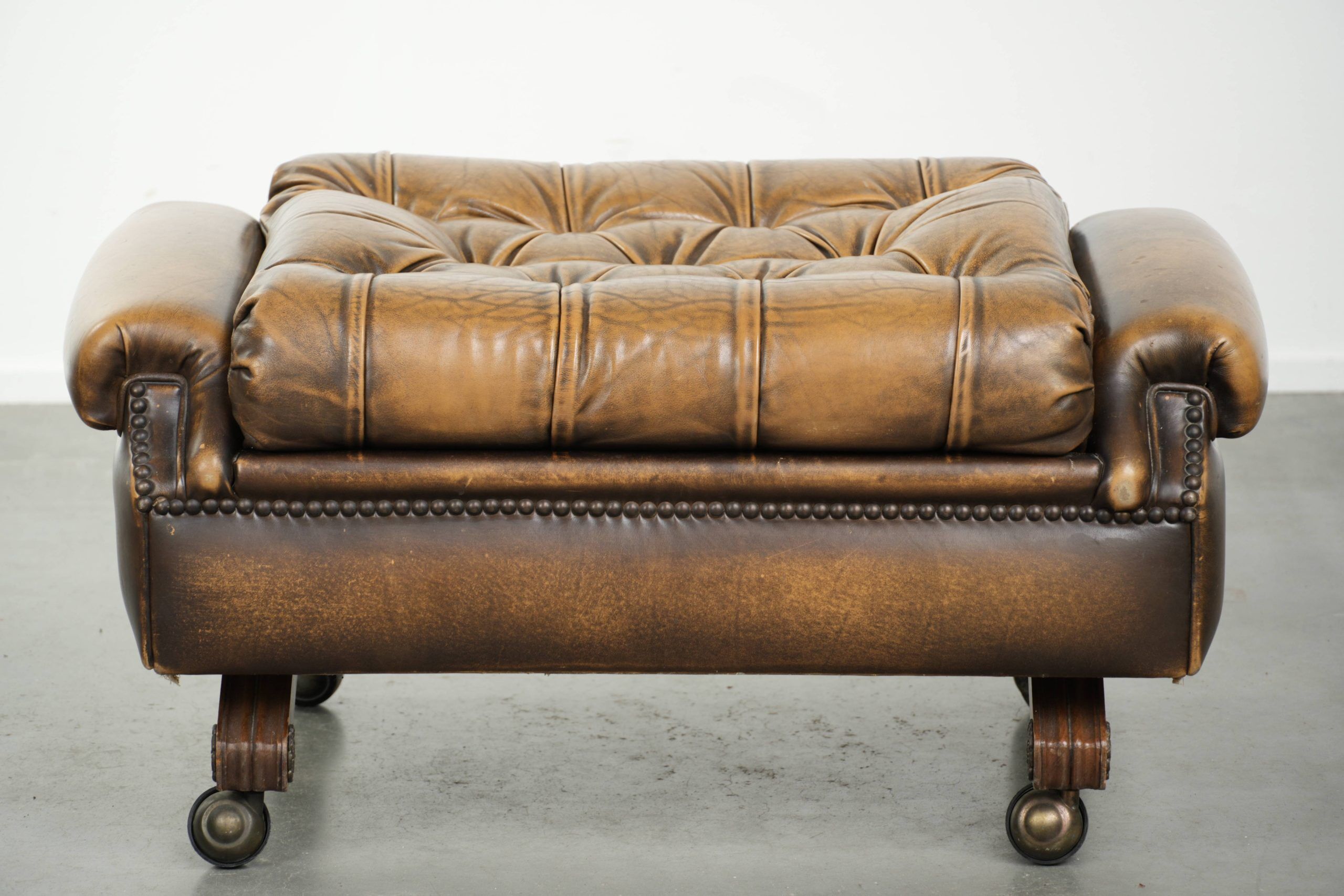 Ottoman chesterfield anglais en cuir élégant, fini avec des clous décoratifs.