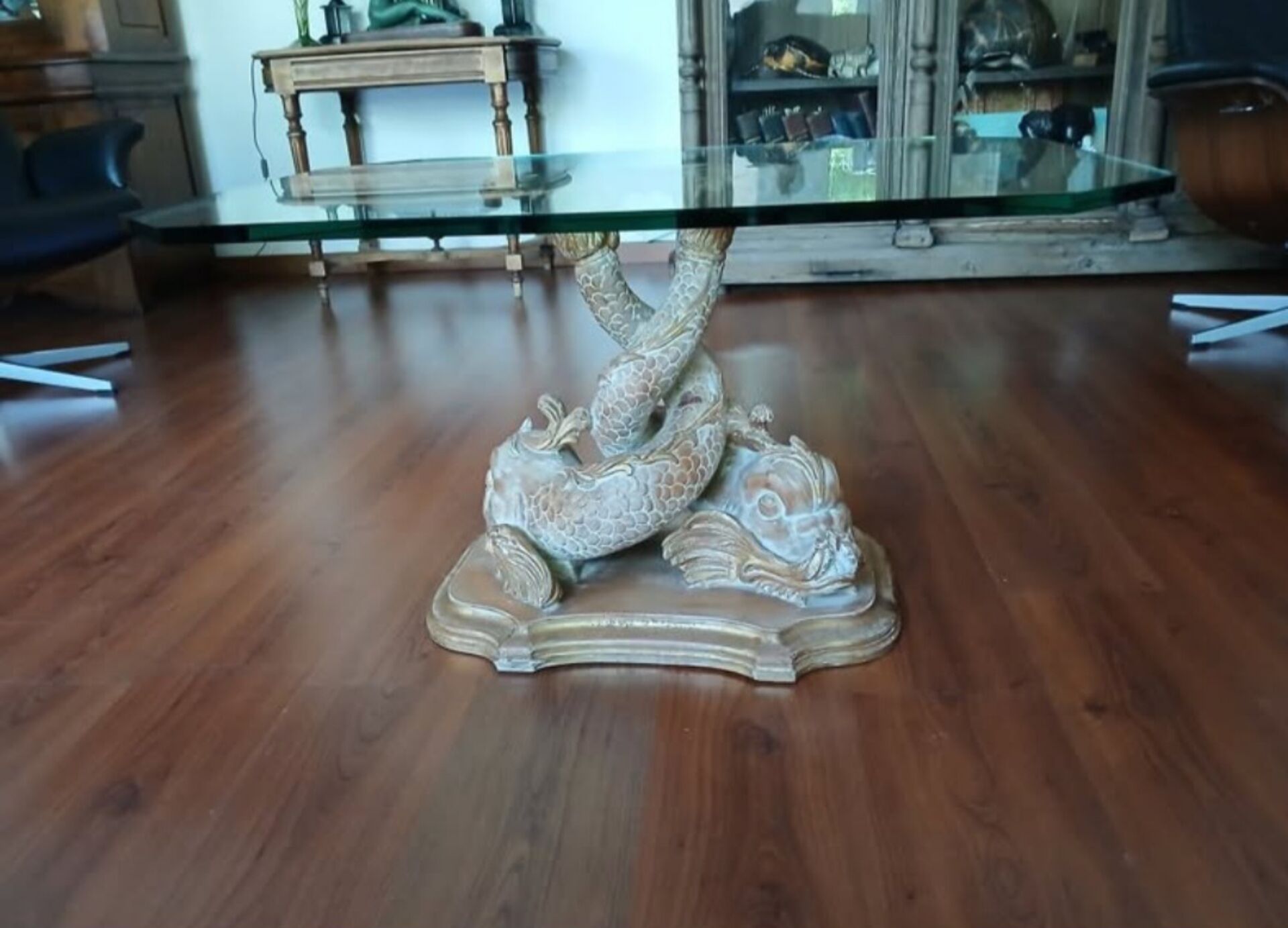 Glass table with carved wooden legs featuring intertwined fish.