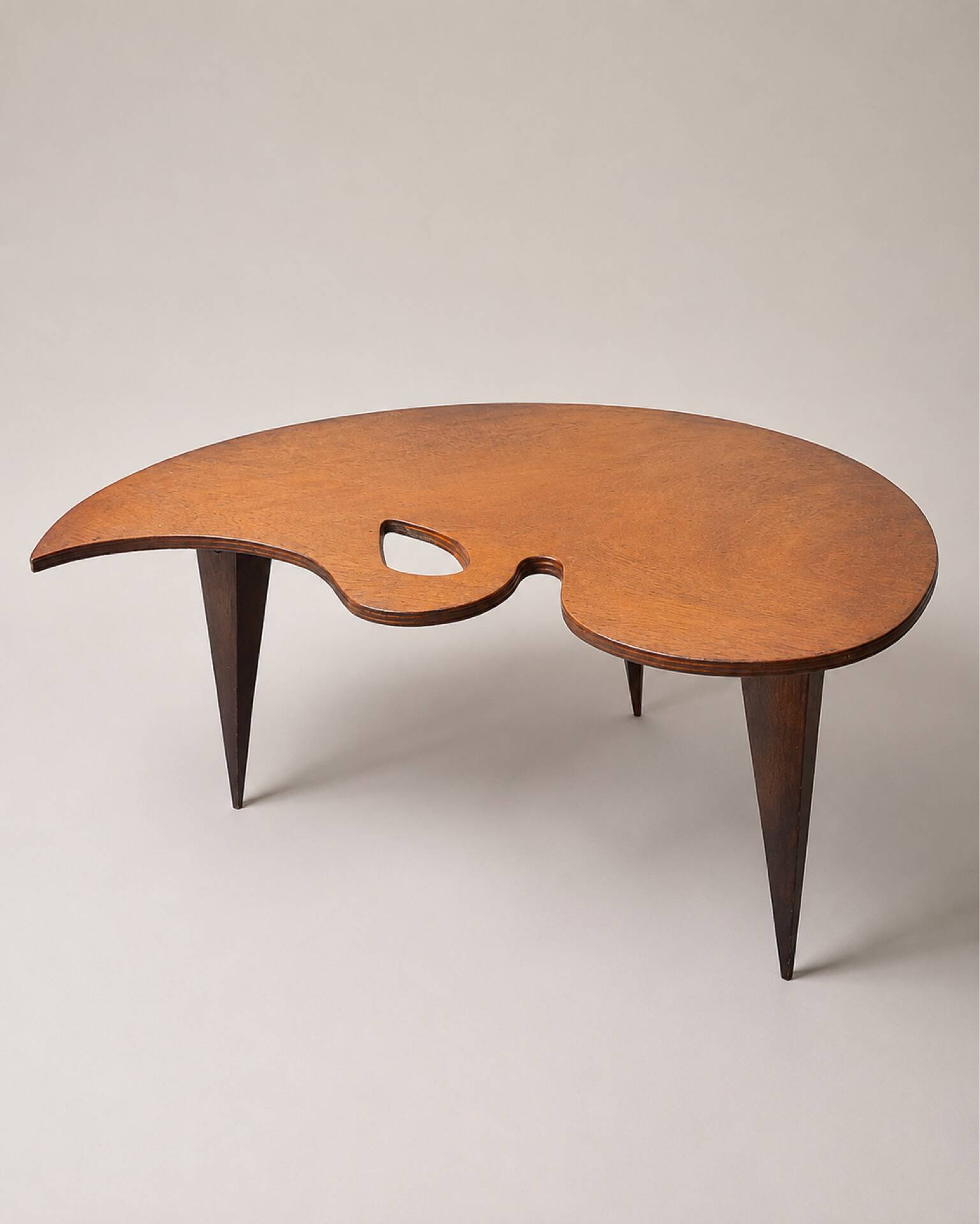 Mid-century coffee table with a palette shape and splayed legs.