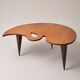 Mid-century coffee table with a palette shape and splayed legs.