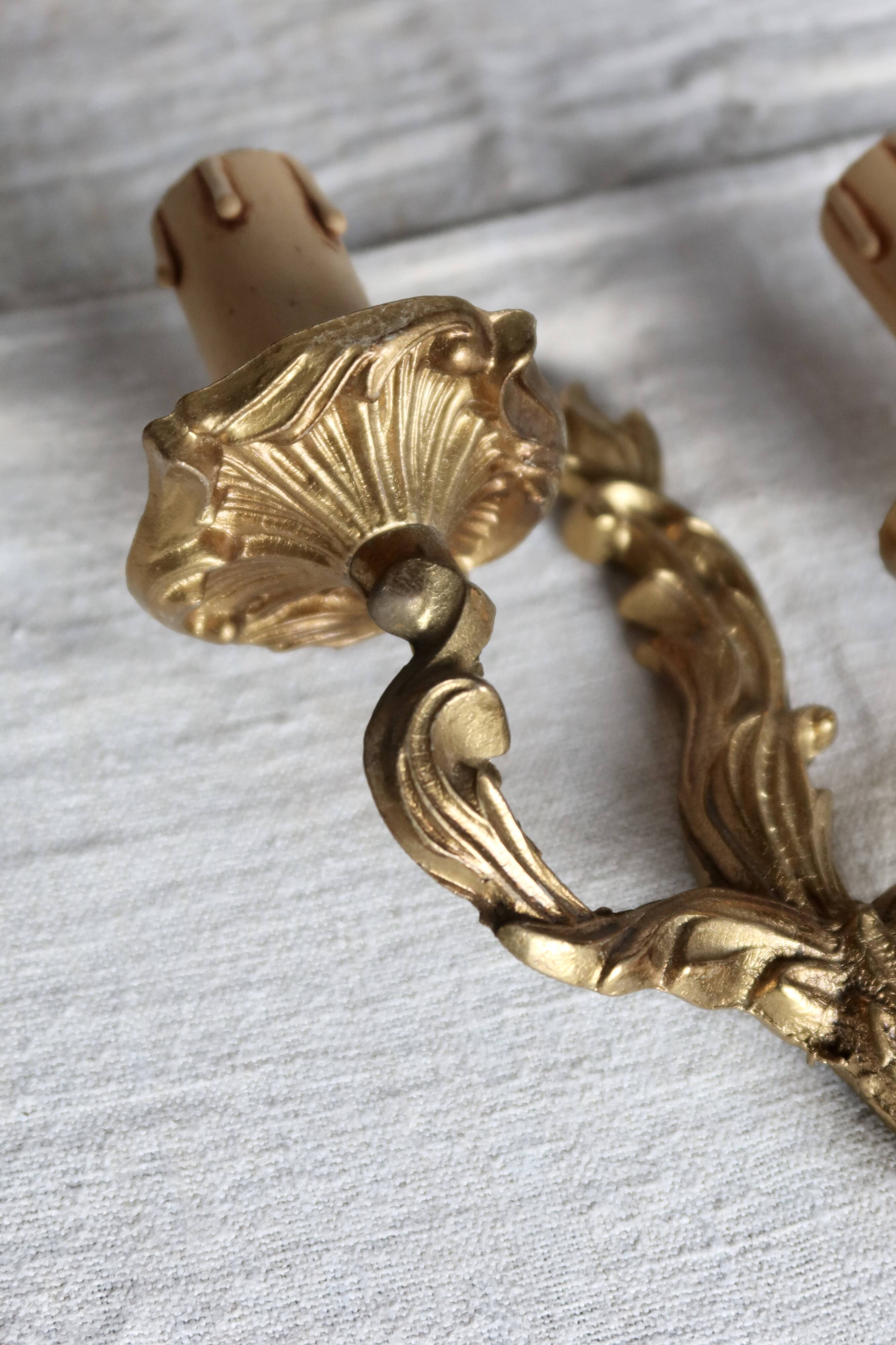 Vintage wall sconce in gold metal with two arms in classic style.