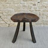 Tripod stool made of solid wood, with a carved seat.