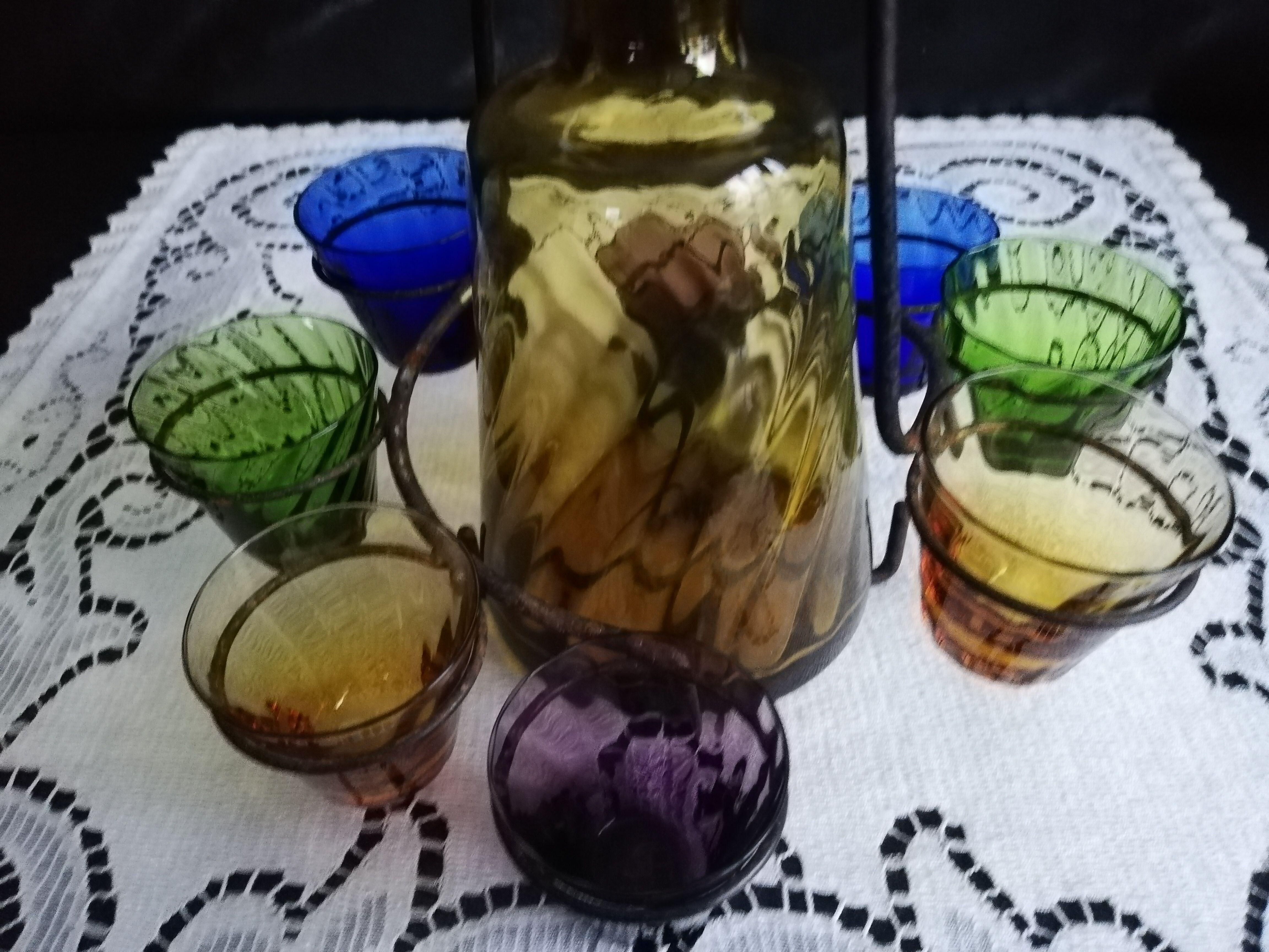 Old Italian alcohol decanter and its colorful glasses