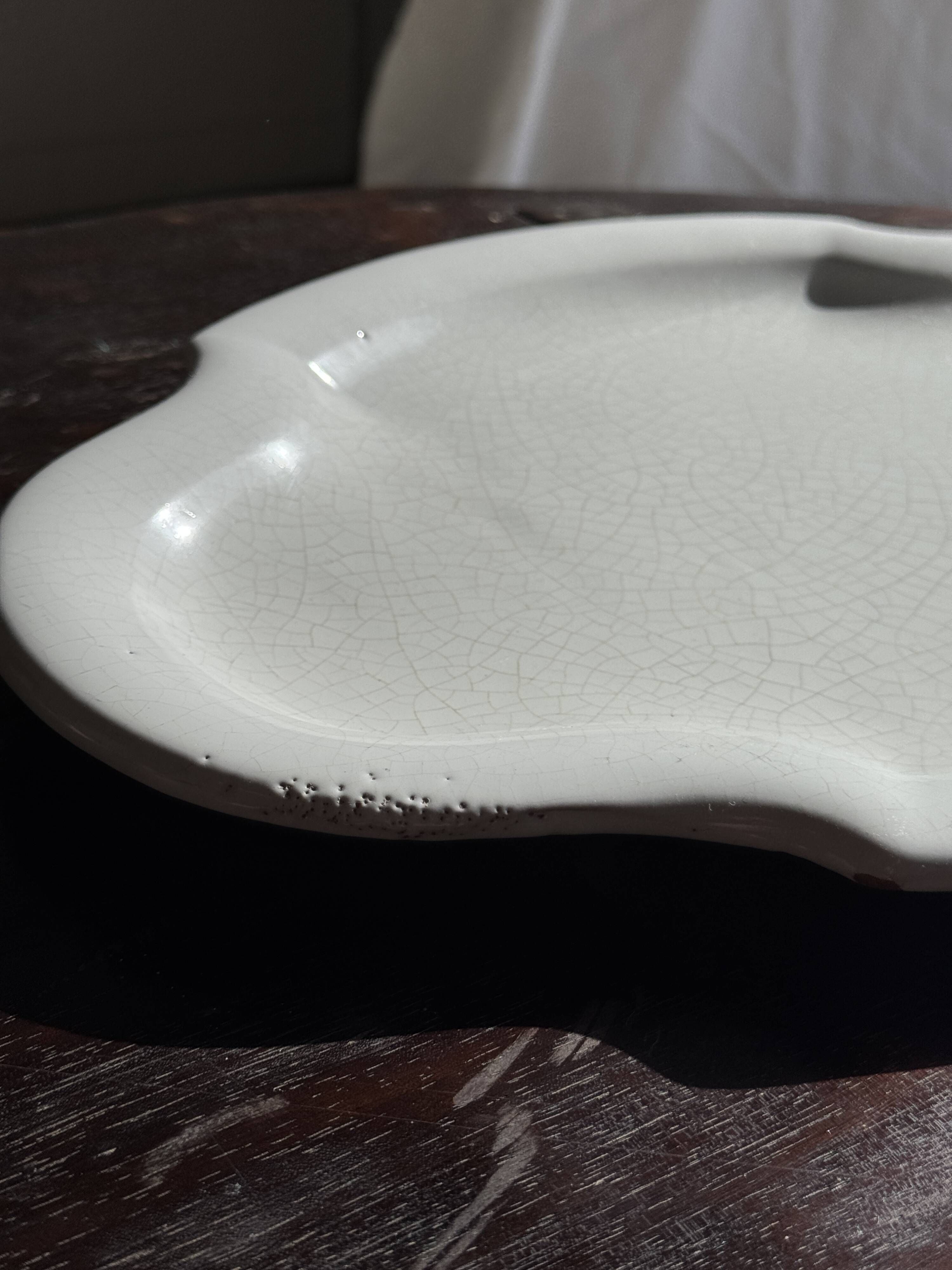 Antique oval-shaped white crackled faience plate with a scalloped edge.