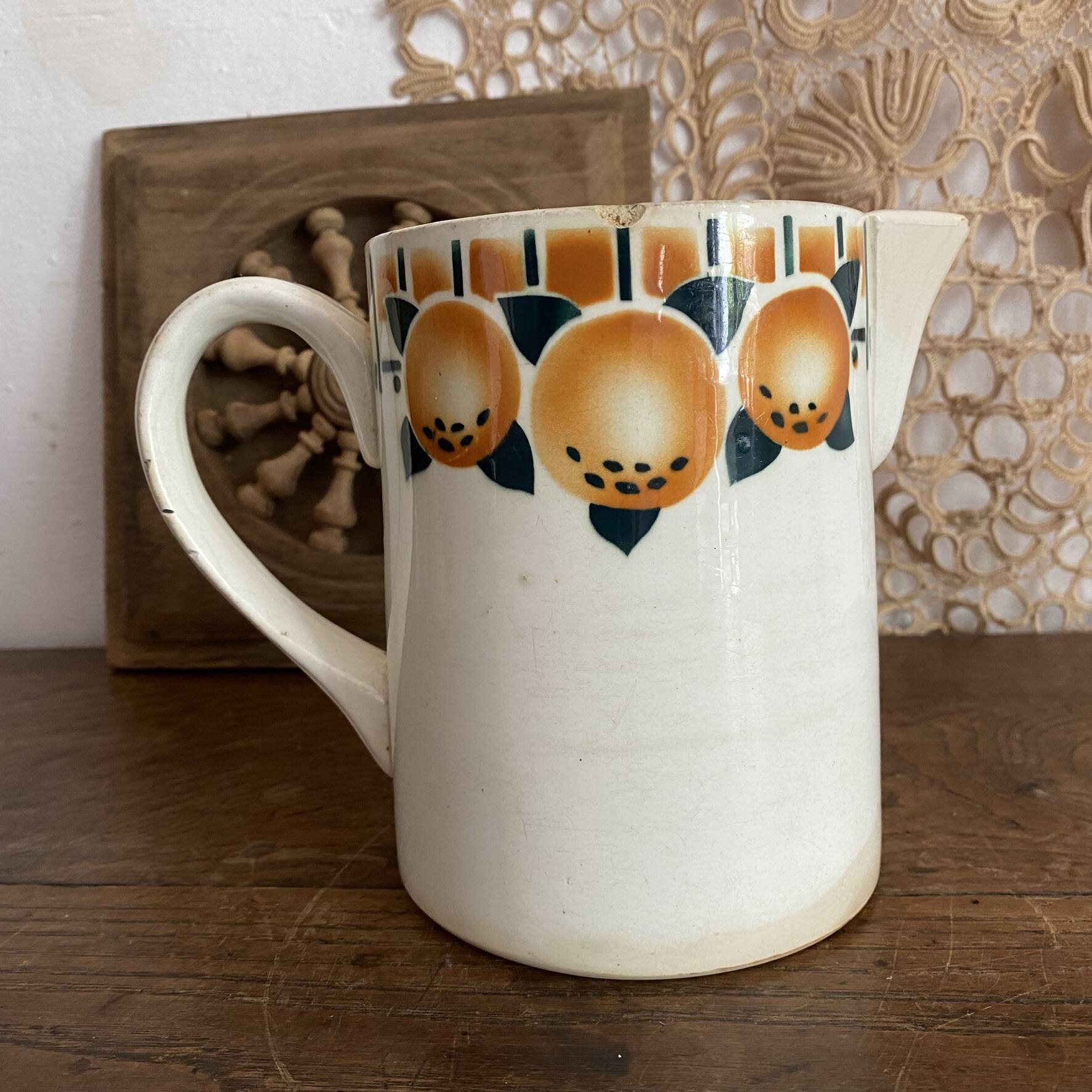 Old ceramic pitcher with orange decoration.