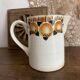 Old ceramic pitcher with orange decoration.