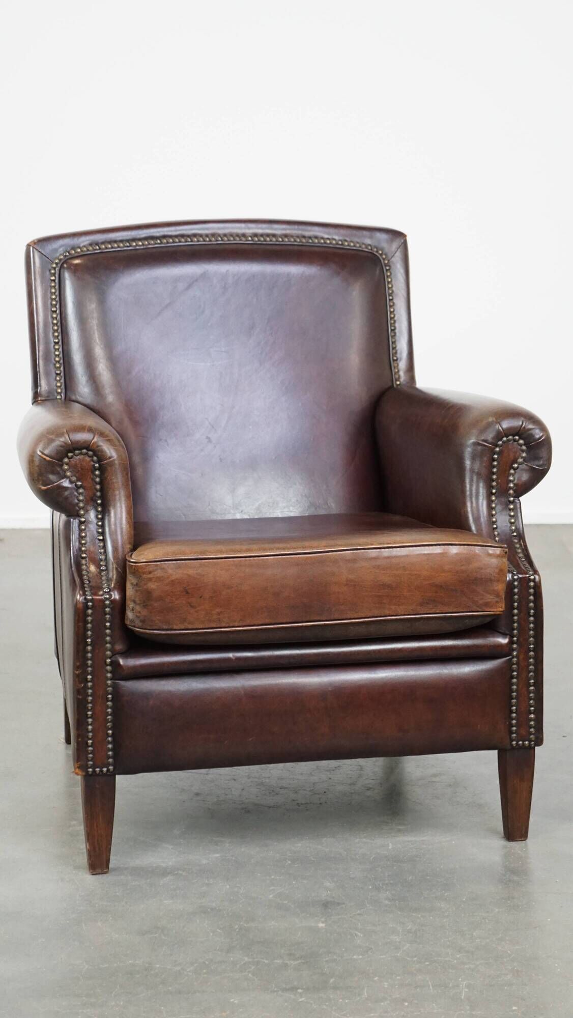 Dark brown sheepskin armchair finished with decorative nails
