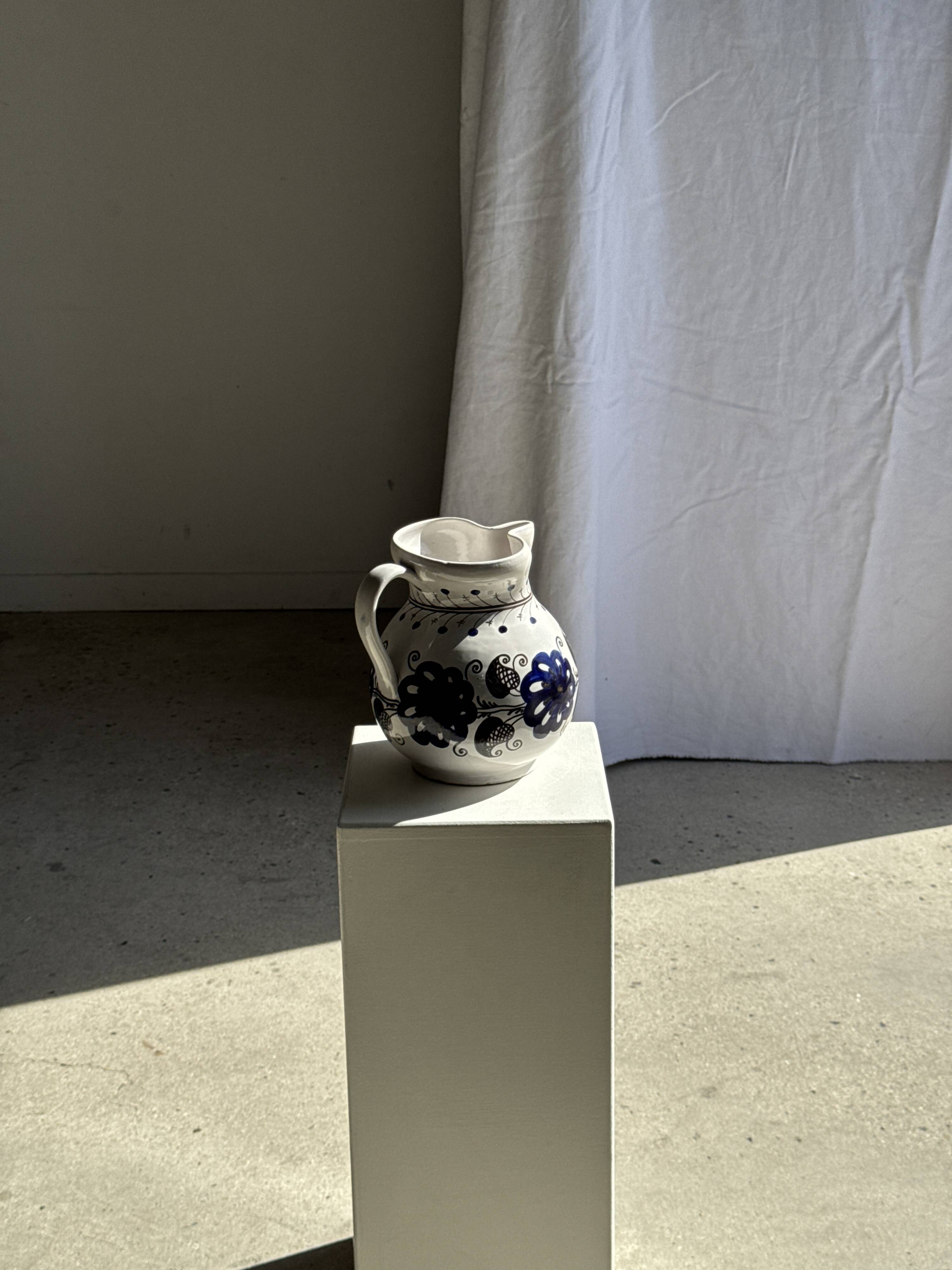 Very large vintage ceramic carafe in white glazed with blue floral decoration.