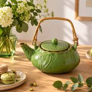 Vintage green teapot with lotus decoration and bamboo handle.
