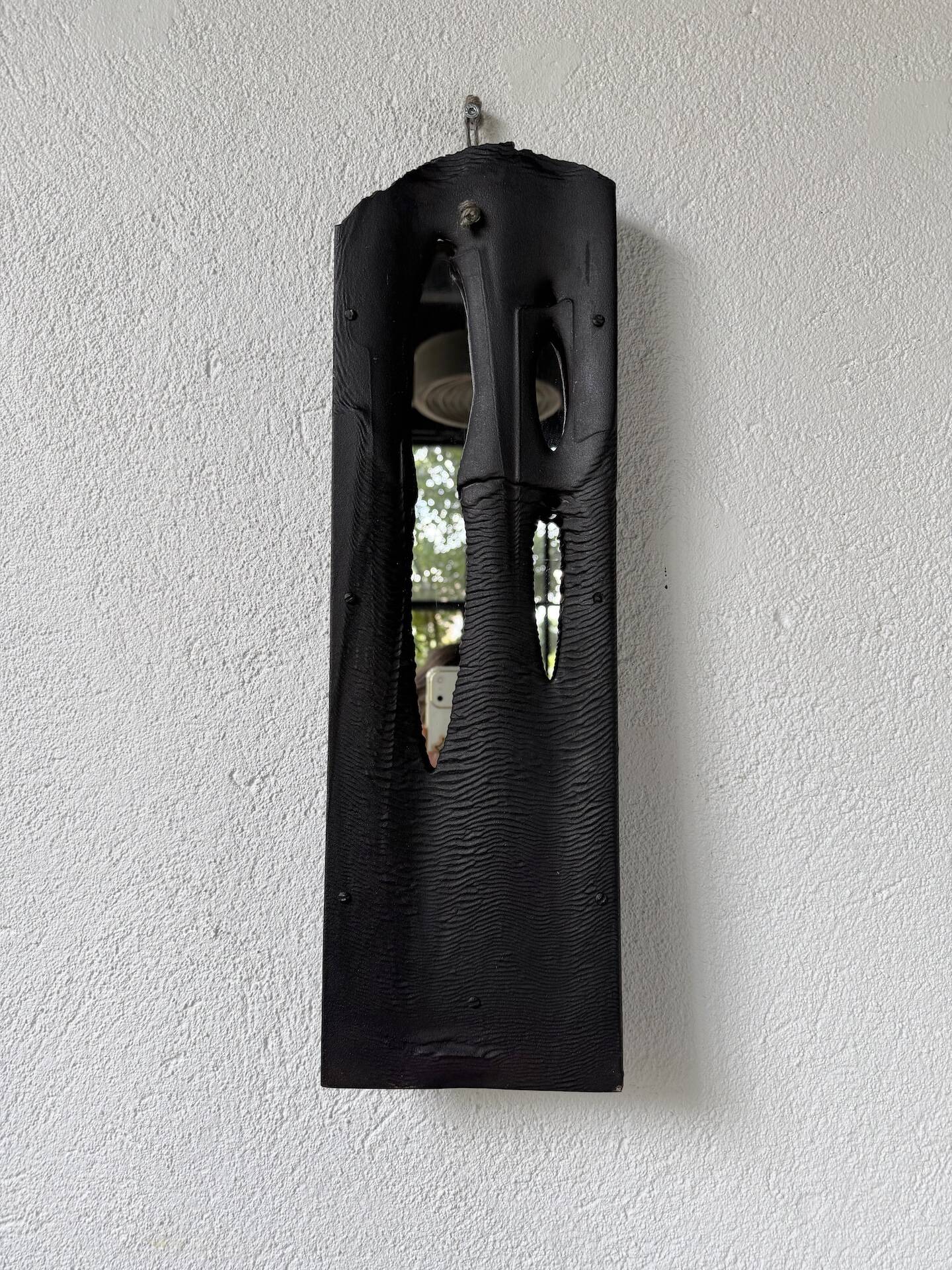 Brutalist hammered mirror, free-form, patinated metal.