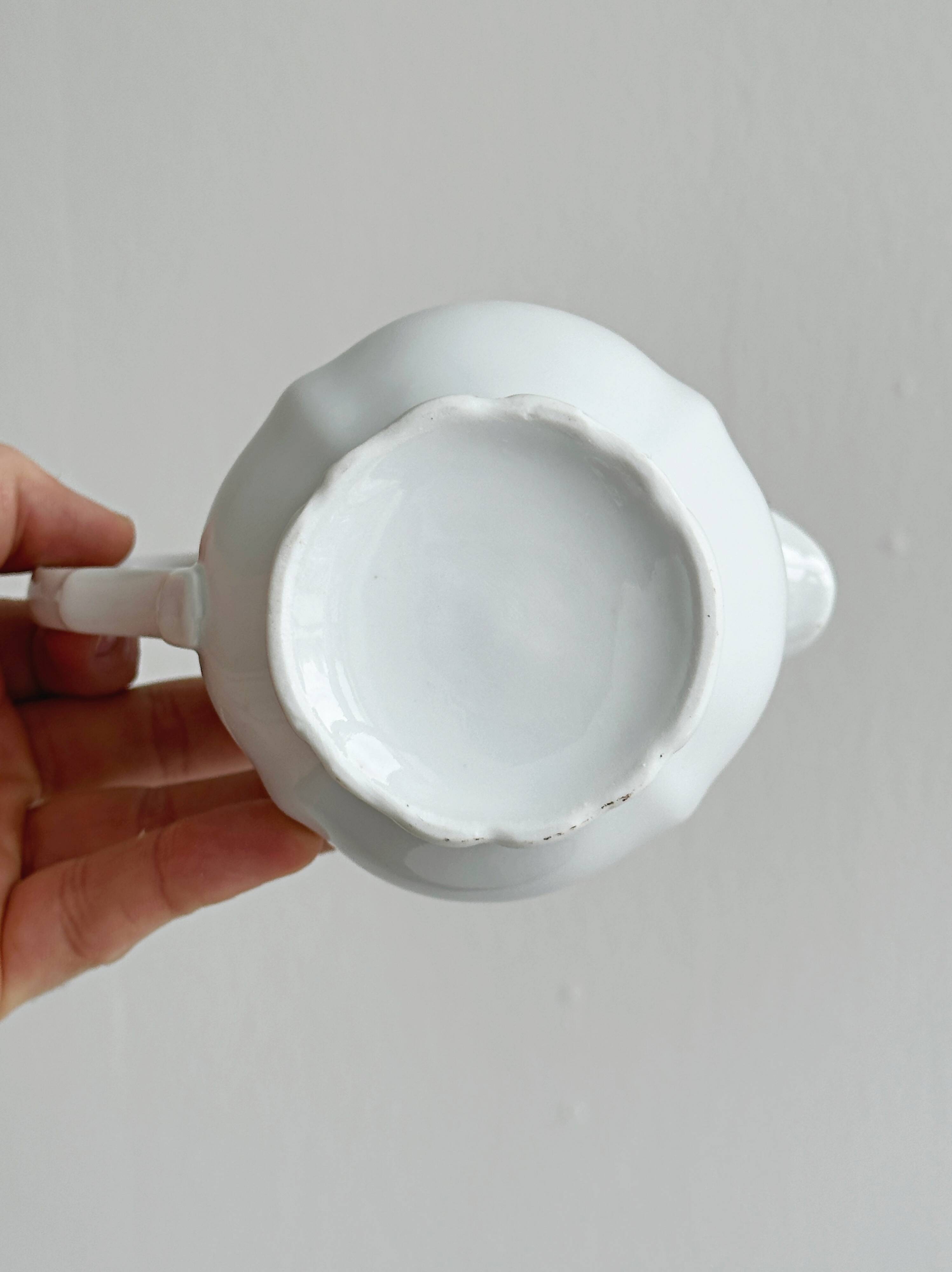 Old white porcelain milk jug, cream jug with relief.