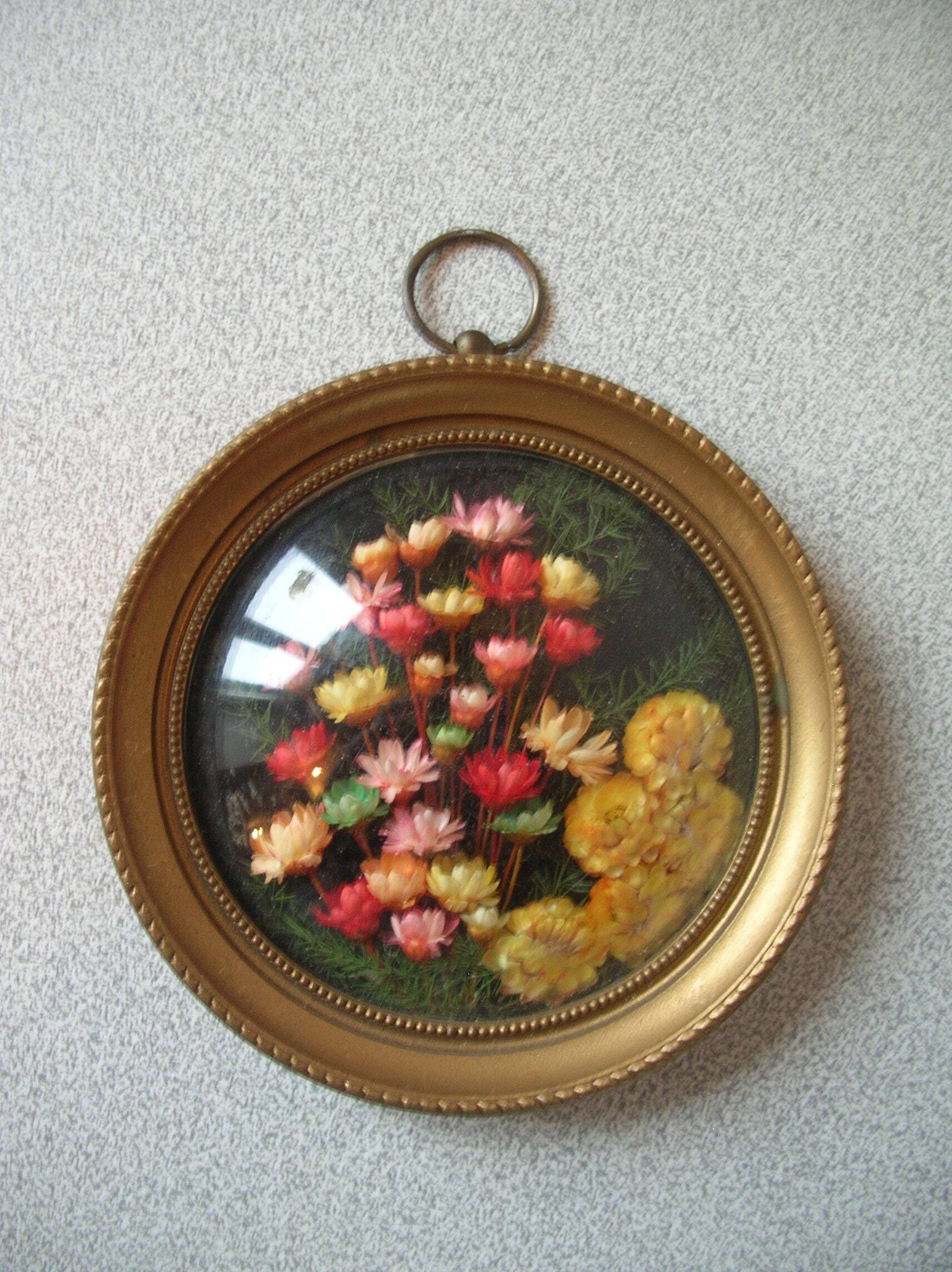 Old medallion frame bouquet of dried flowers glass and plastic retro decoration