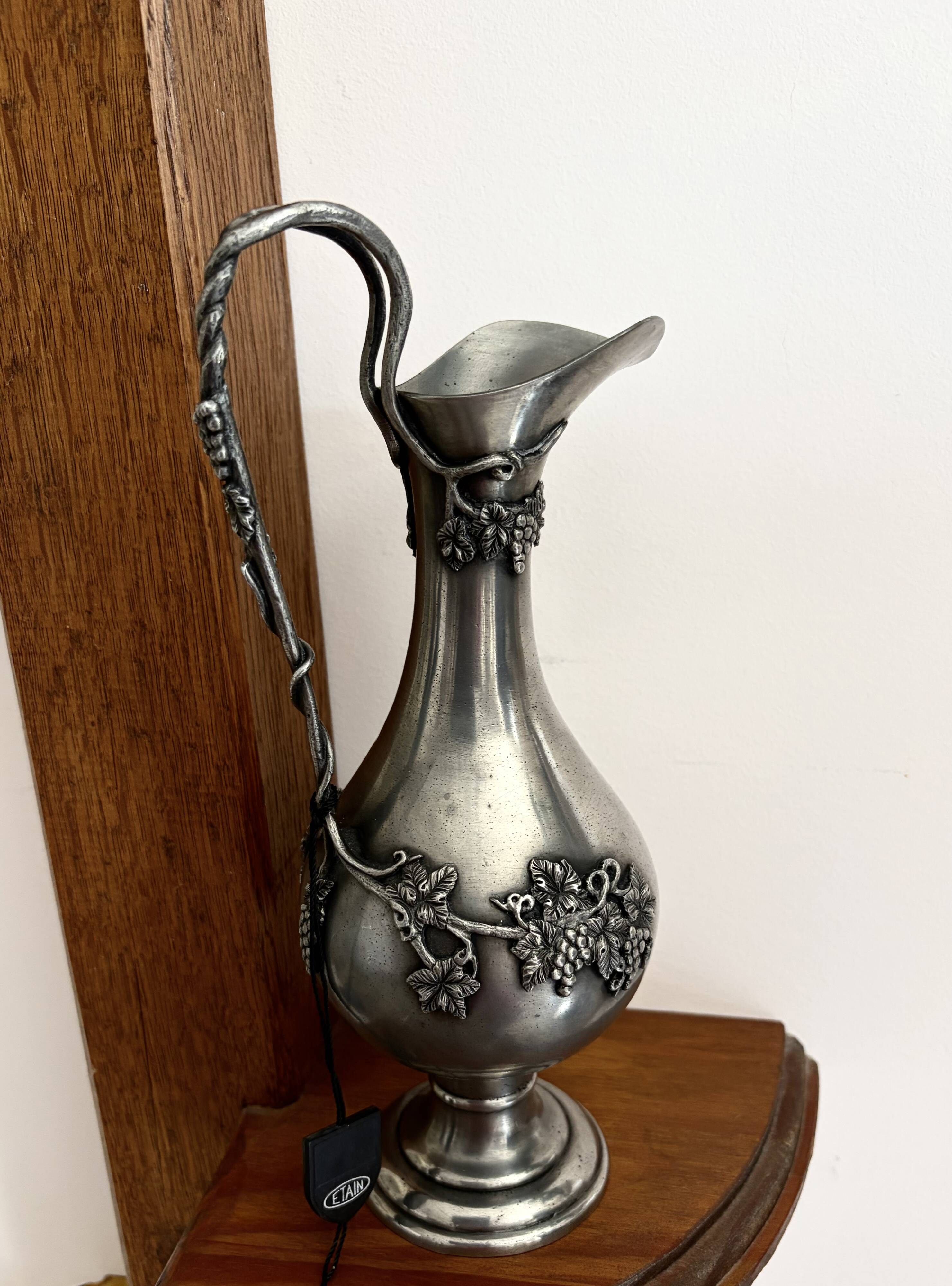 Ewer in pewter surrounded by vine branches with g