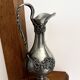 Ewer in pewter surrounded by vine branches with g