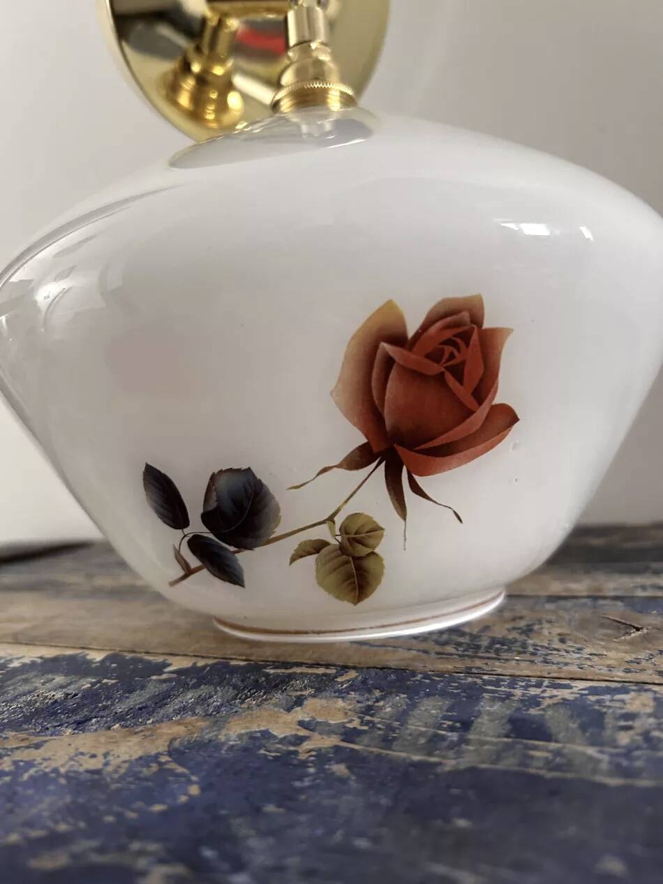 Golden tilting wall light with flowered globe