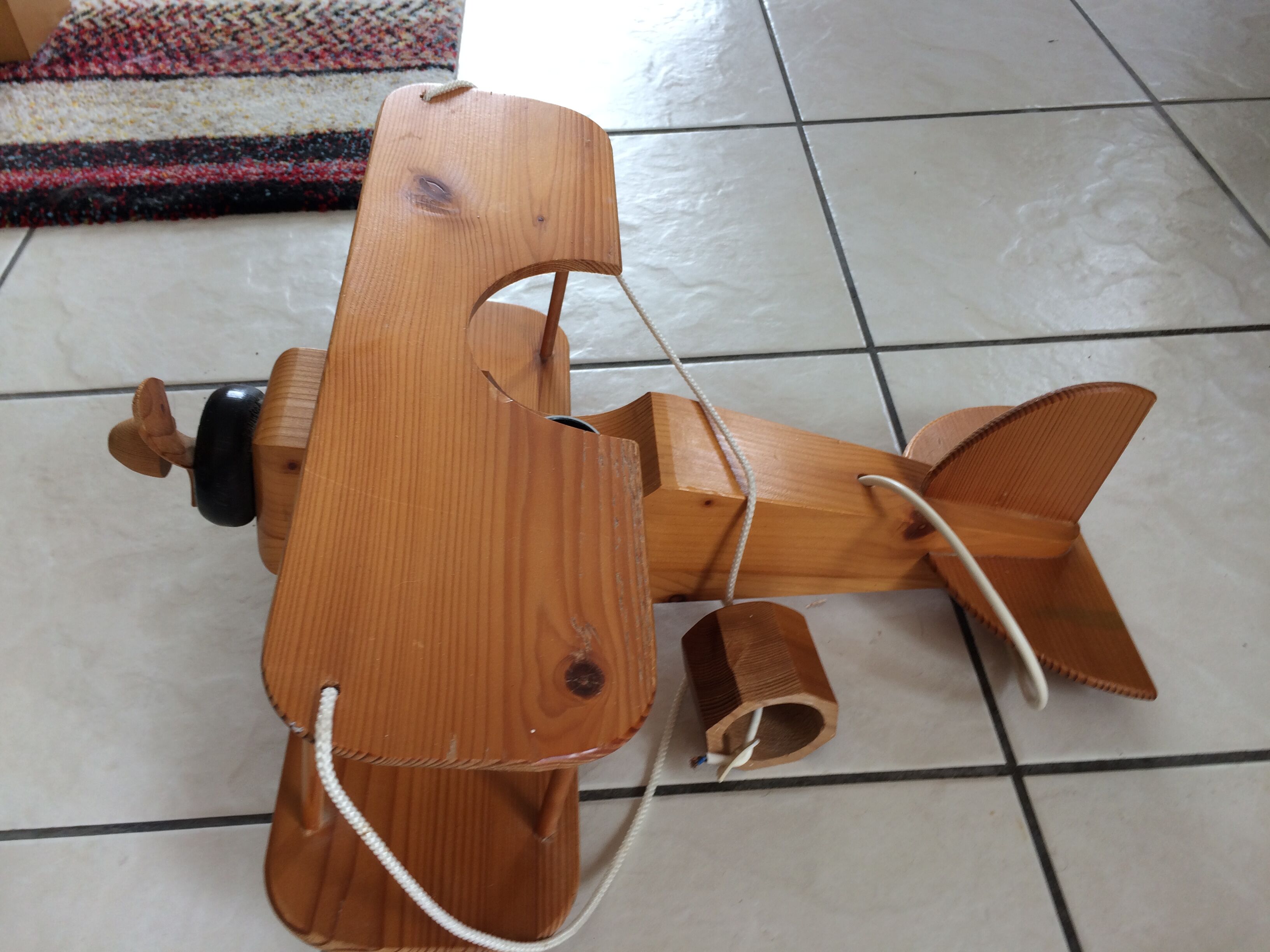 Light wood hanging in the shape of an airplane. Electric.Year 70.