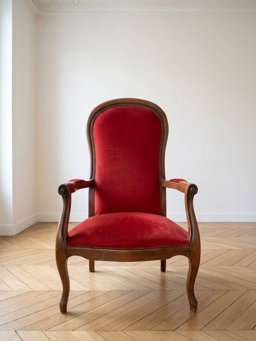 Antique armchair in carved wood and red fabric.