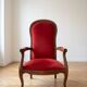 Antique armchair in carved wood and red fabric.