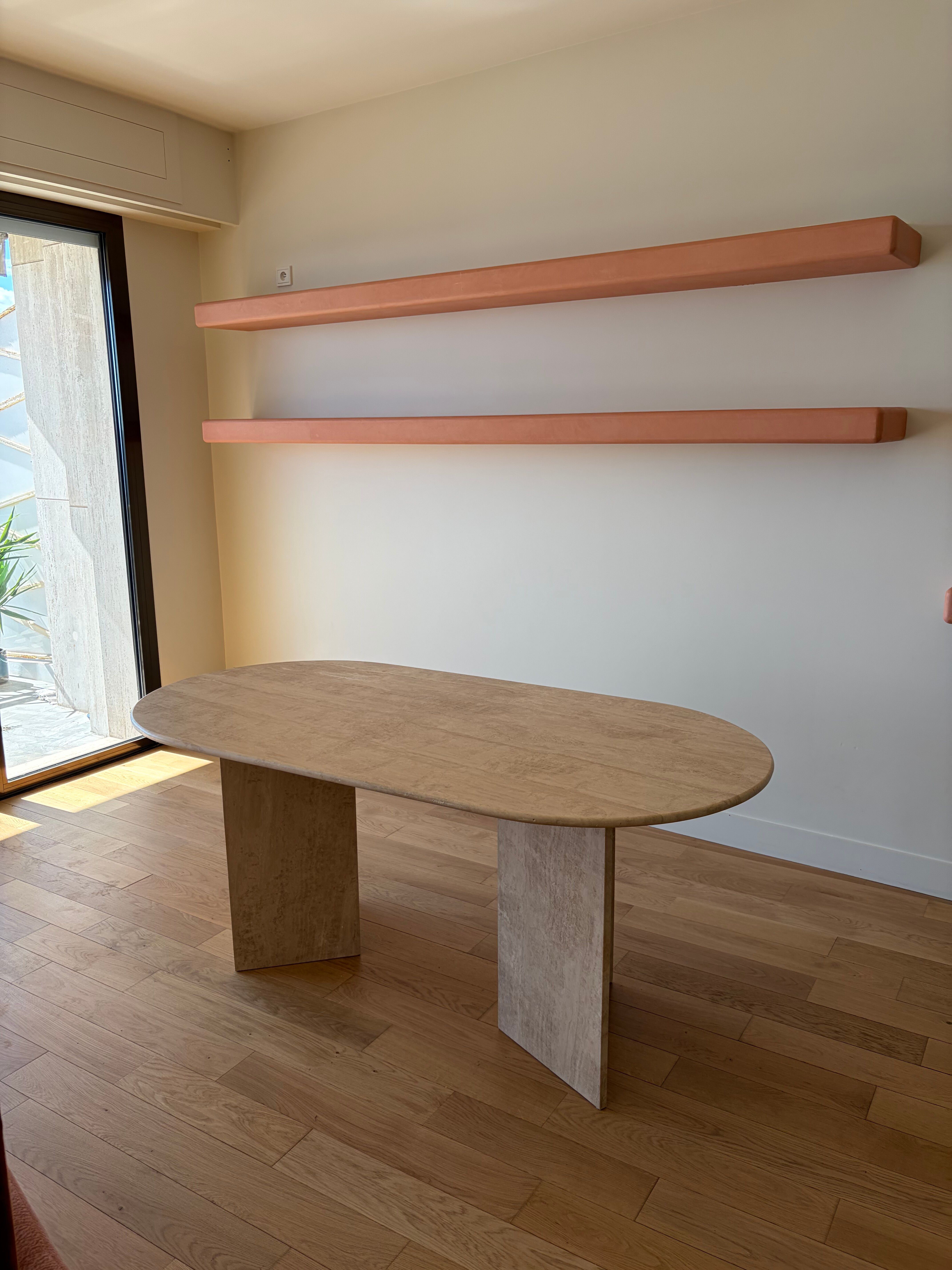 Oblong dining table in beige travertine.