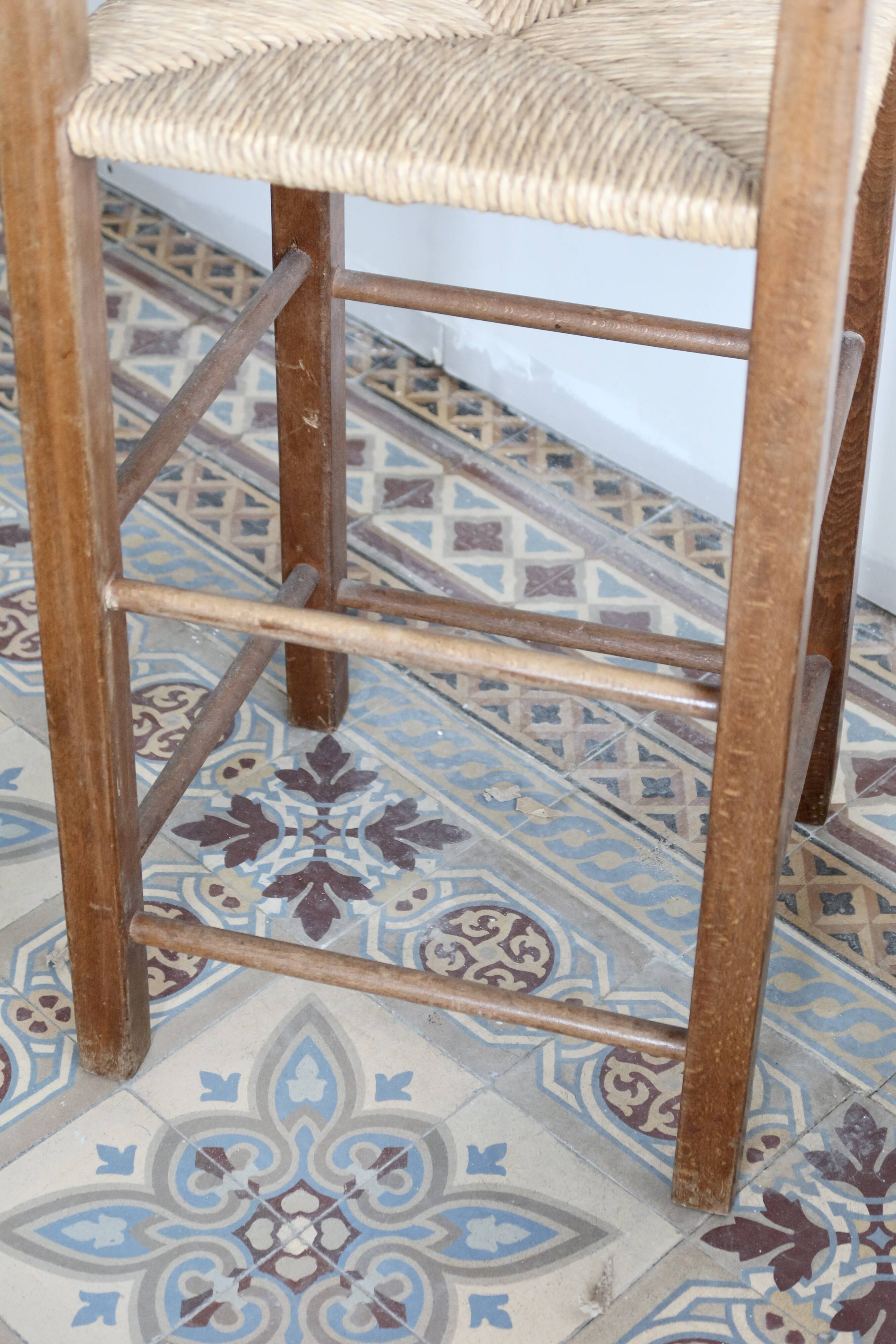 Vintage wooden high chair for children with a straw seat.