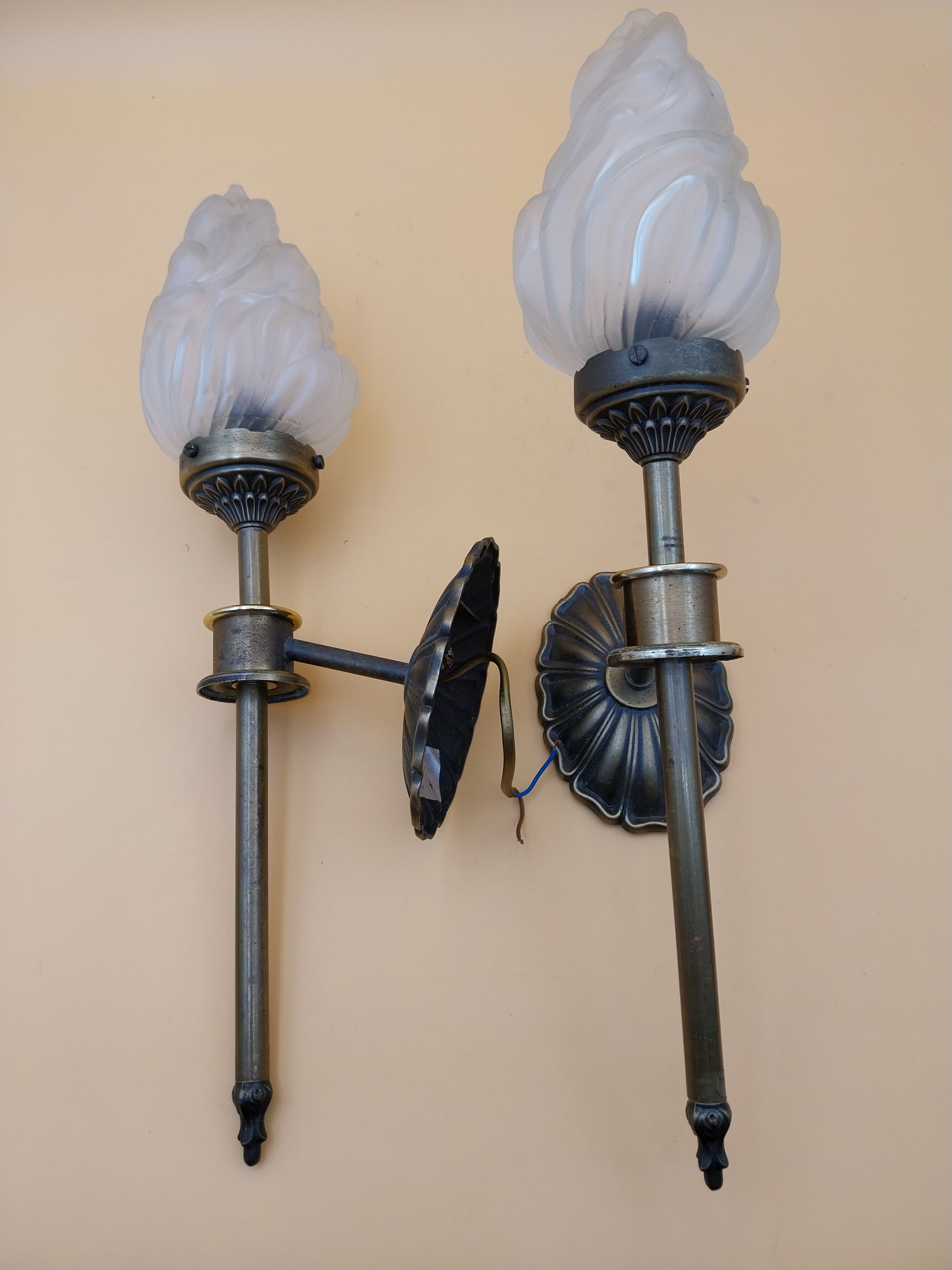 Pair of brass torch wall lights with globe flame.