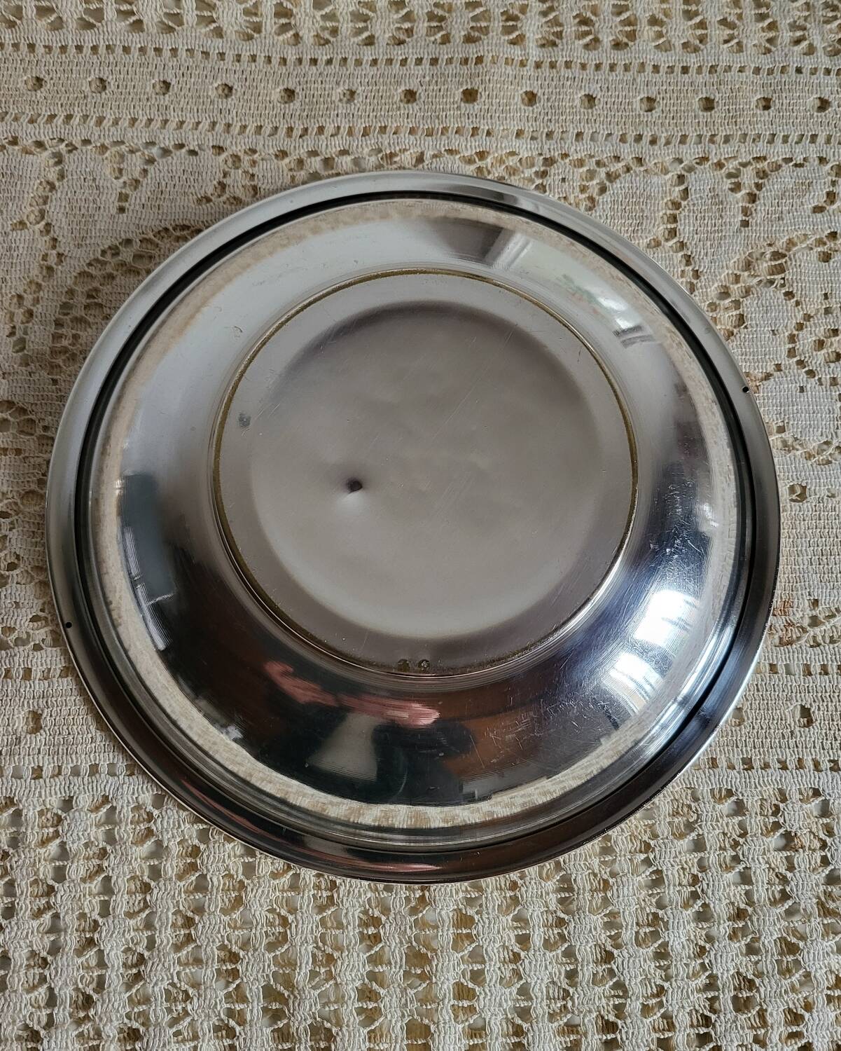 Shallow round metal plate with pearl bead decoration.