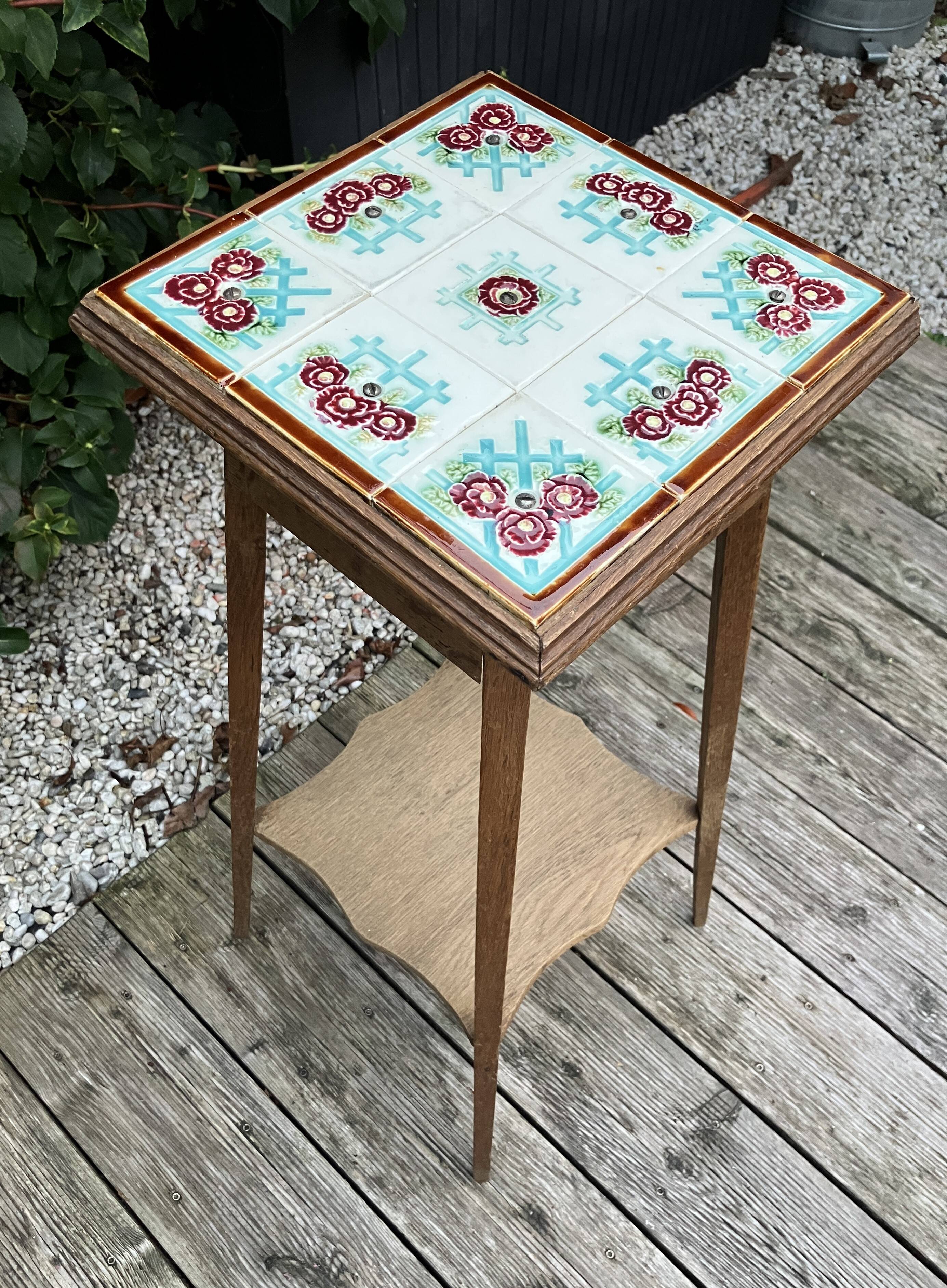 Antique wooden plant stand with ceramic tiles.