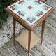 Antique wooden plant stand with ceramic tiles.