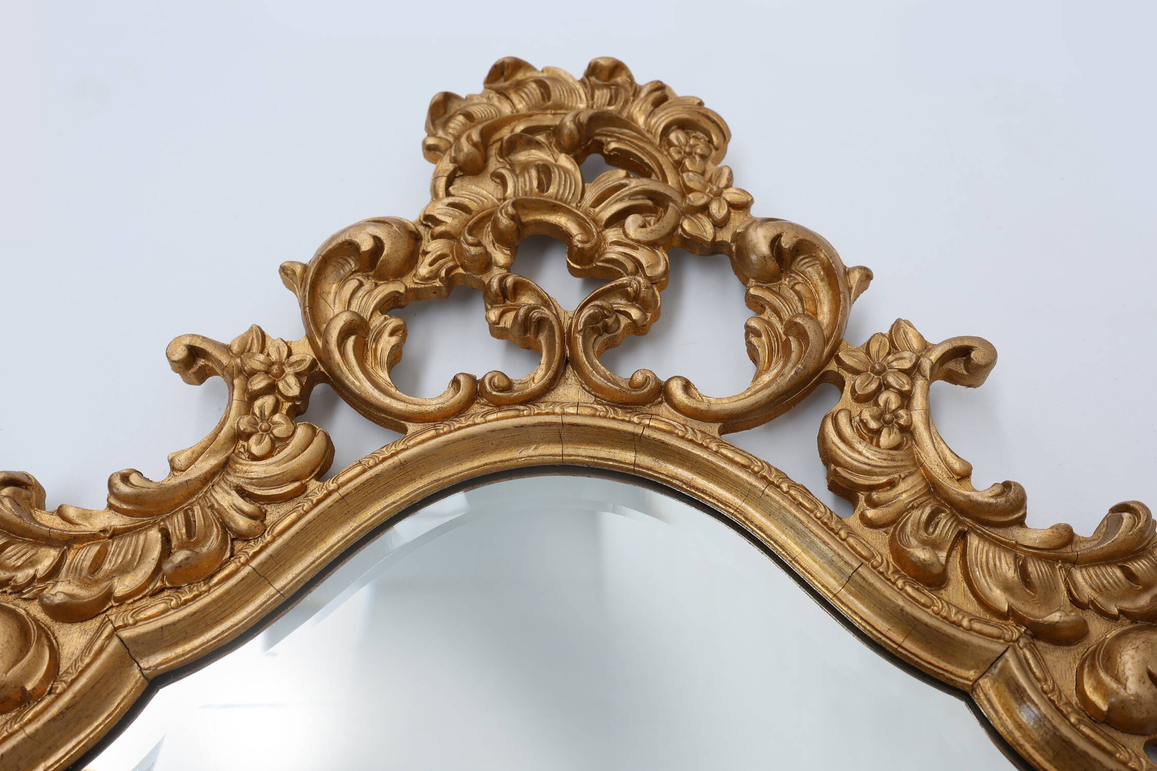 French Rococo or Baroque style facet-cut crest mirror in gilded carved wood