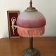 Old table/bedside lamp with glass shade with pink gradients and fringes.
