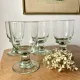 4 stemmed glasses made of handcrafted blown glass in green hue.