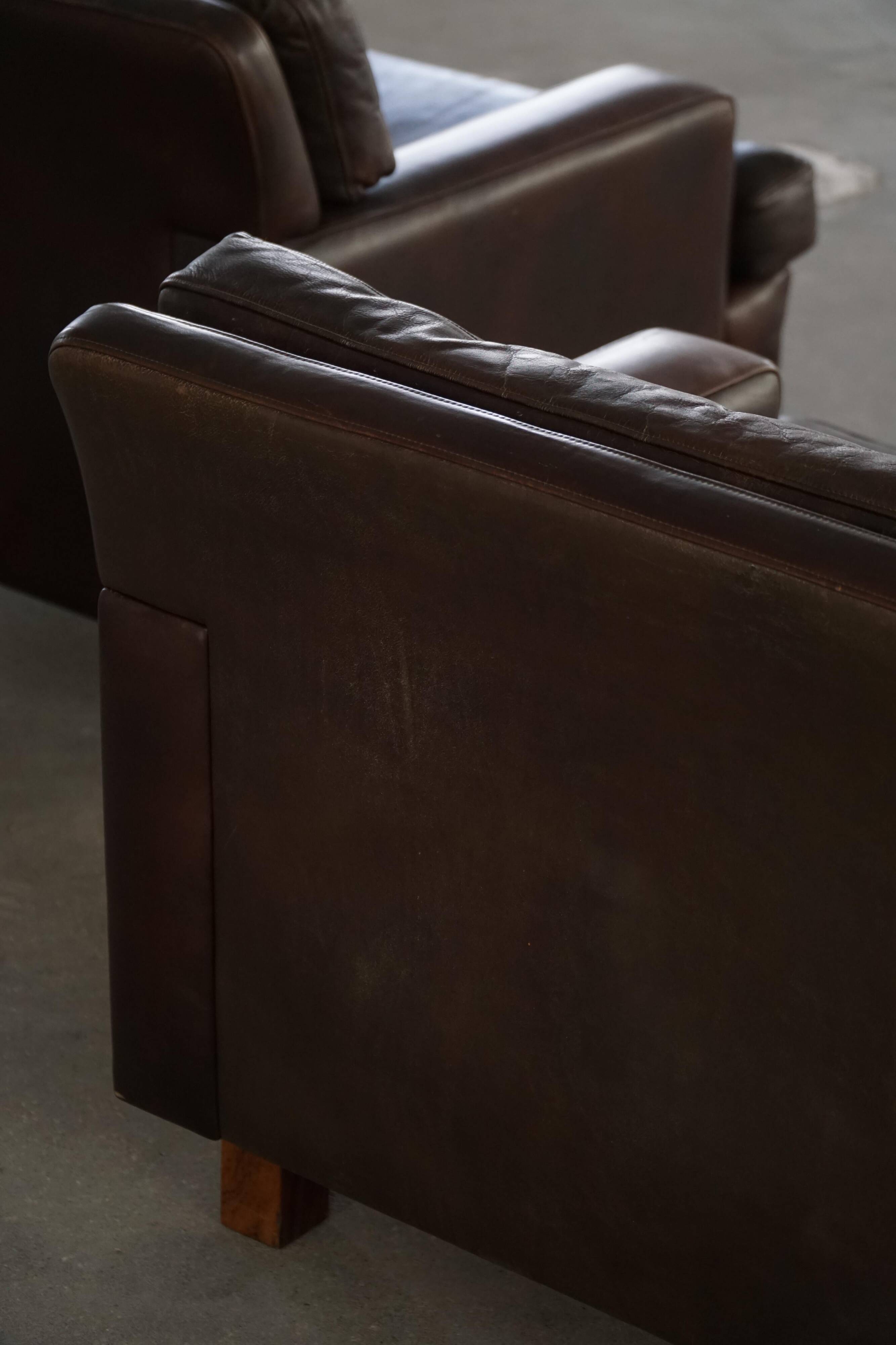 Pair of modern Danish lounge chairs in dark brown leather and rosewood, 1960s.